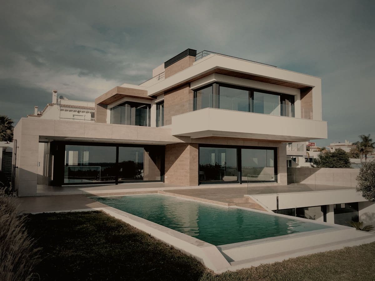 A Finlay Realty villa at dusk, its lit interiors reflected in a still garden pool.